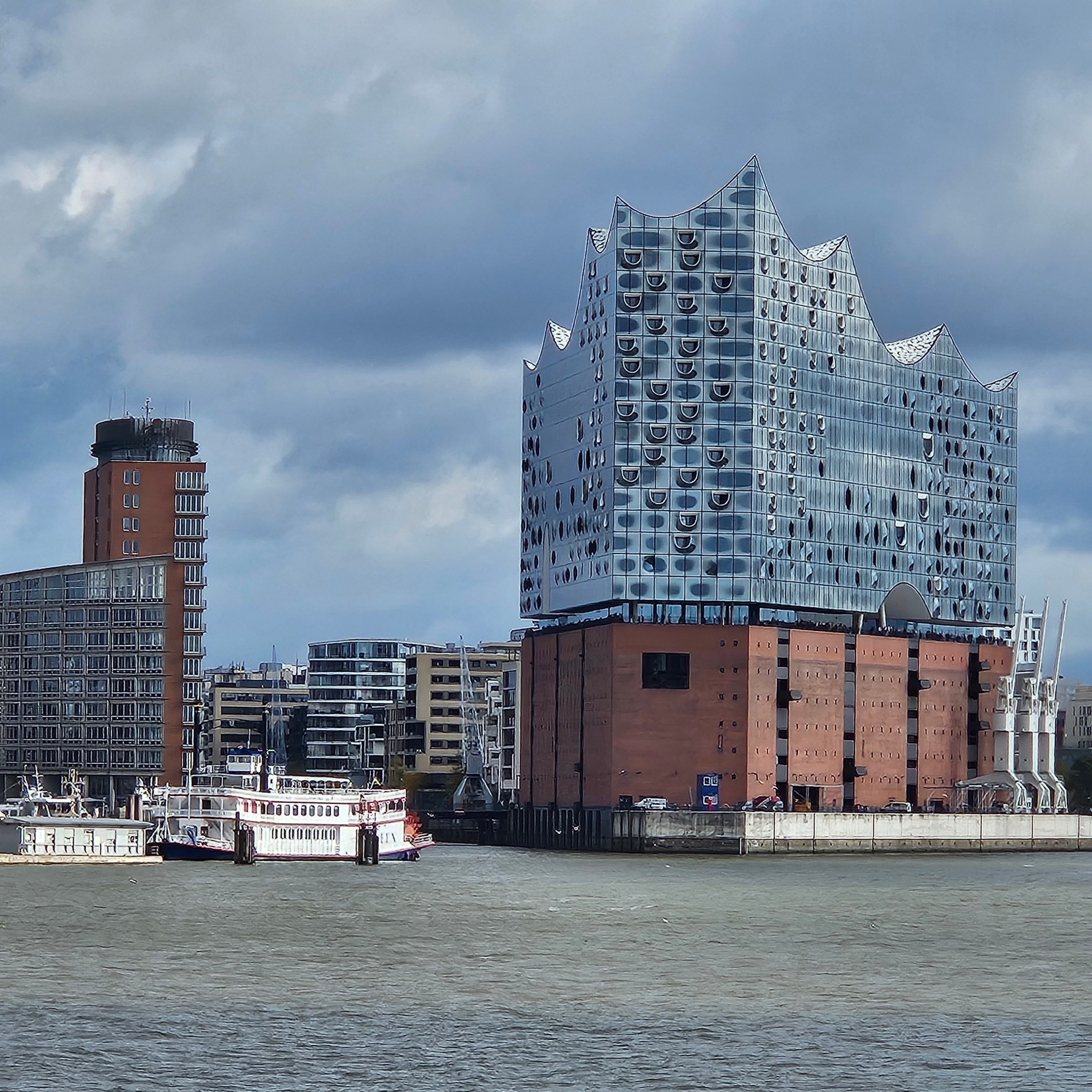 Elbphilharmonie und Hafengebäude unter wolkigem Himmel