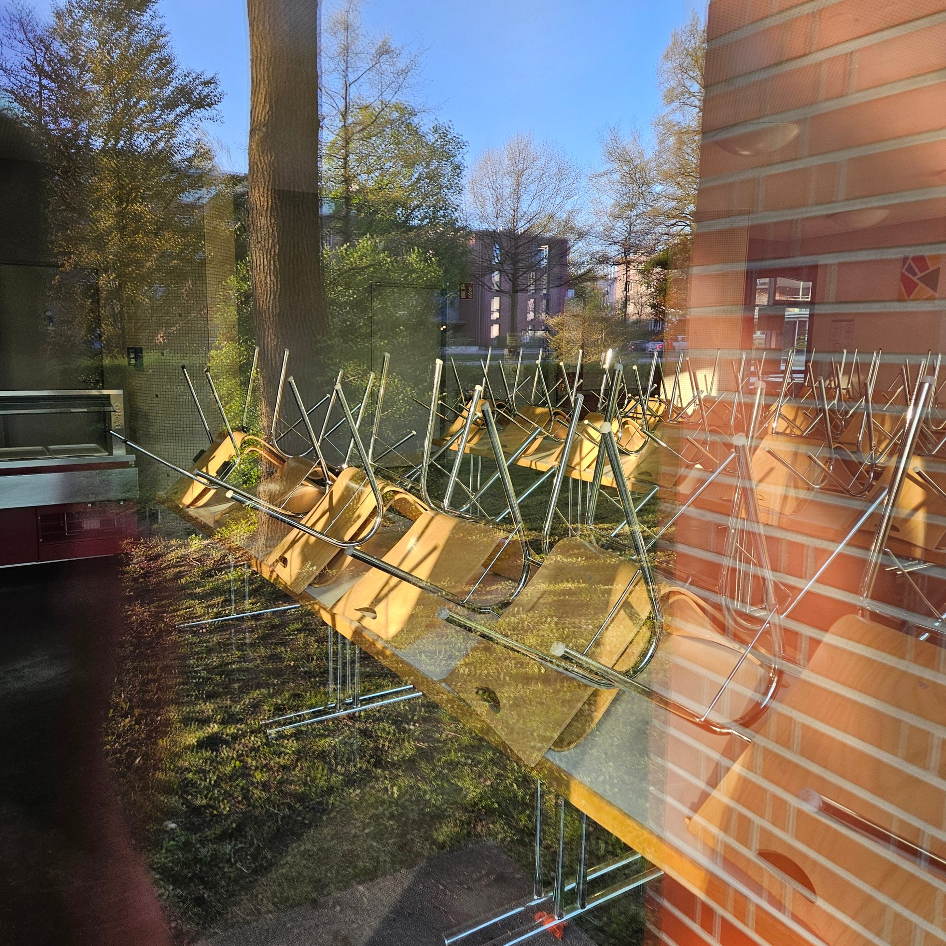 Schulraum und Außenbereich als Spiegelung in einer großen Glasscheibe