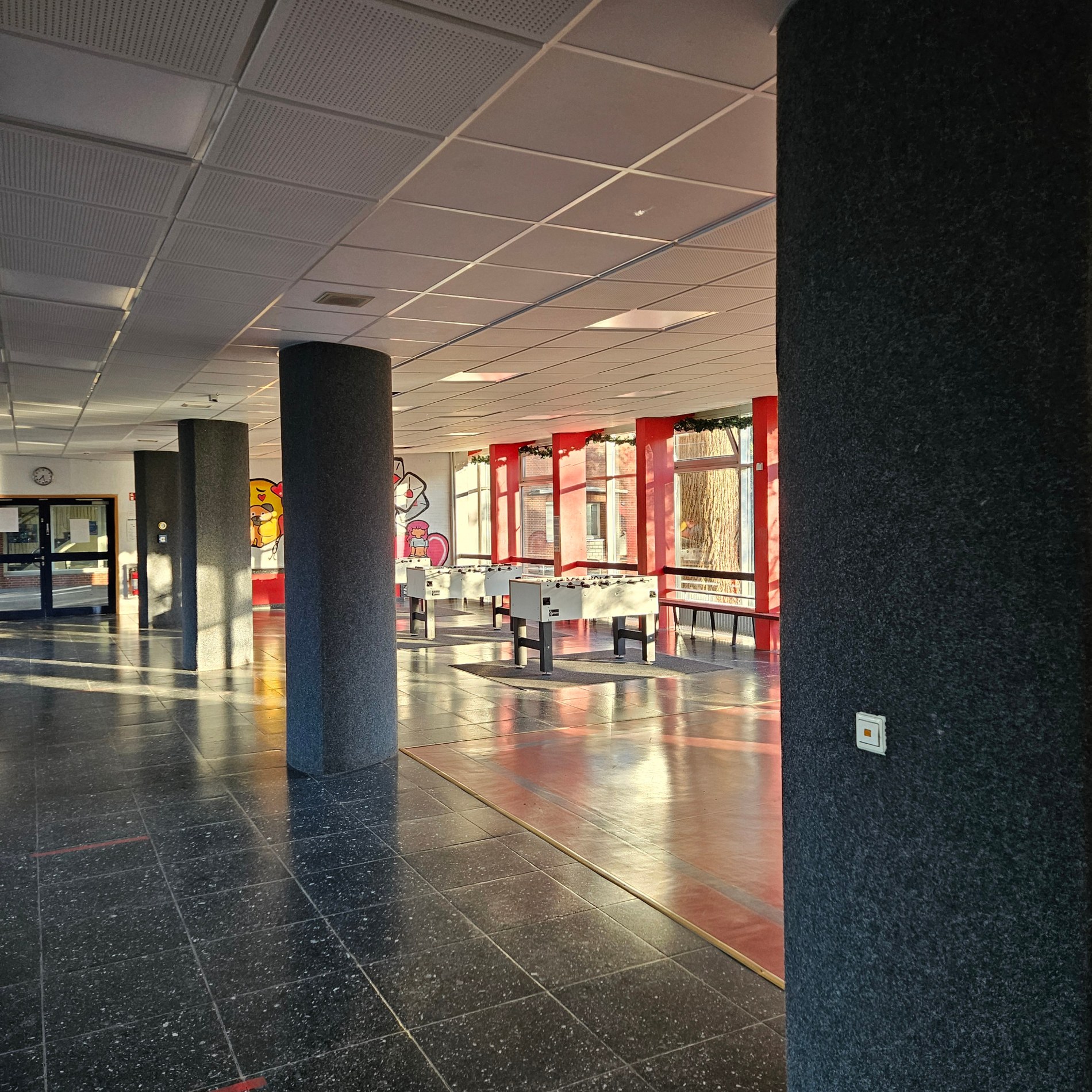 Großer Aufenthaltsraum mit schwarzen Säulen und Tischfußballgeräten